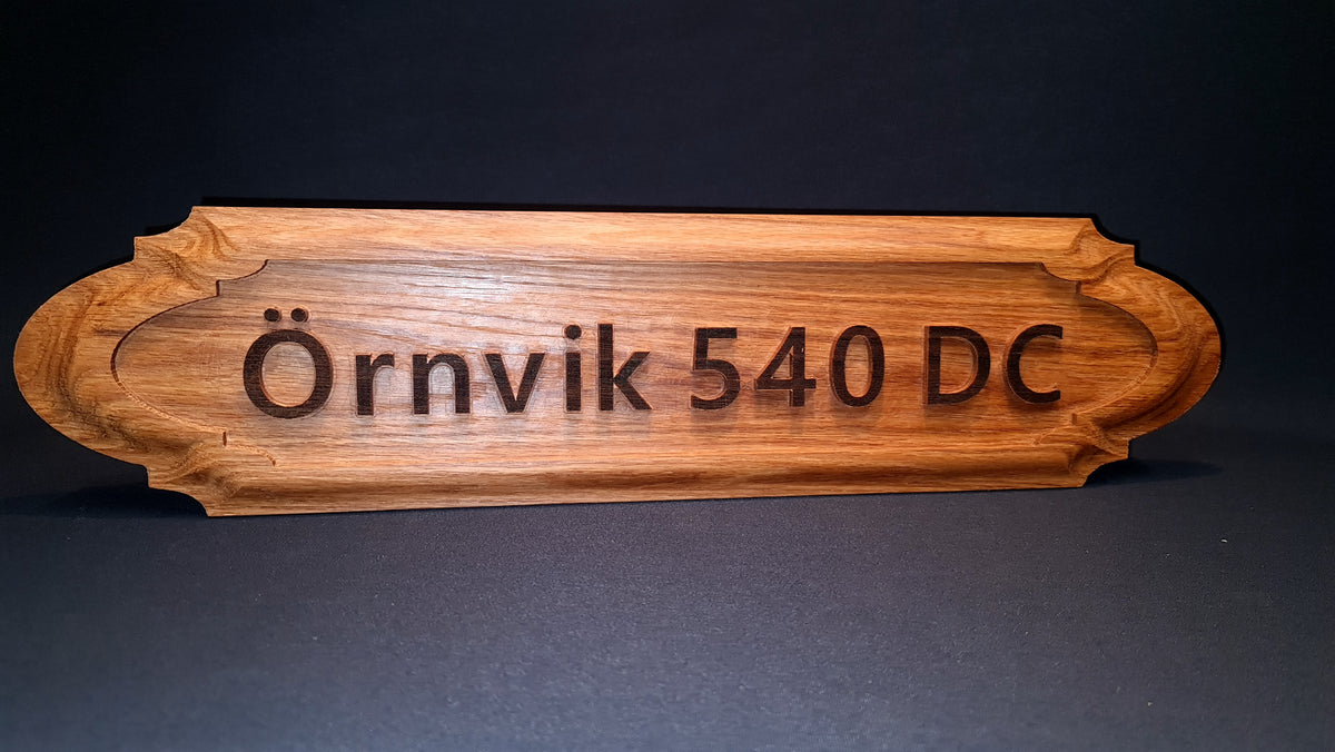 Närbild på det gedigna hantverket och den unika 3D-profilen hos en kundanpassad namnskylt i massivt trä skräddarsy online